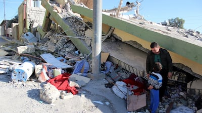 An Iraqi Kurdish man stands with his son near a building destroyed in earthquake at Darbandikhan town, near Sulaymaniya city, northern Iraq. Afan Abdulkhaleq / EPA