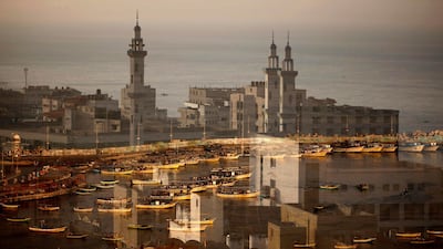 A mosque is reflected on a window with the Gaza City port in the background on May 16. AFP