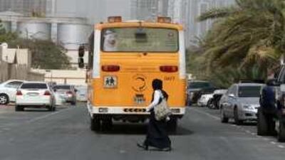 A schoolgirl crosses behind the bus that has just dropped her in Dubai's Al Quoz district.