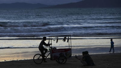 An ice-cream seller rides his cart as people gather on the second day of Eid Al Fitr on Lhoknga beach in Aceh province. AFP