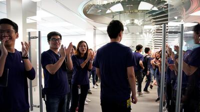 Staff members clap customers through the door at an Apple Store in Shanghai. Aly Song / Reuters