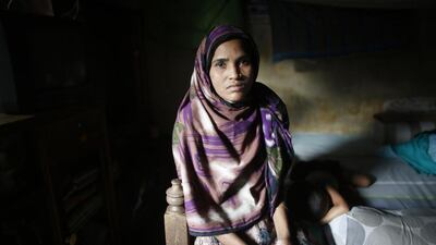 Nilufar Yesmin, 36, who was rescued from the rubble of the collapsed Rana Plaza building, sits inside her slum house in Savar. Nilufar, who is unable to work due to a spinal injury sustained from the accident last year, says she has not received any compensation.
