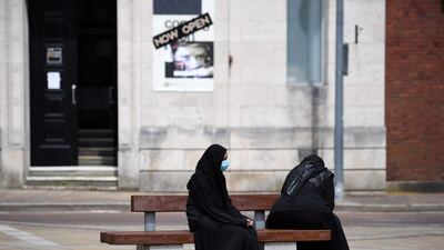 Women wearing a face covering sit on a bench in Blackburn. AFP