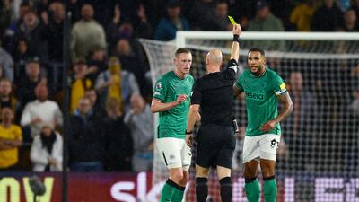 Newcastle United's Dan Burn is shown a yellow card by referee Anthony Taylor. Reuters