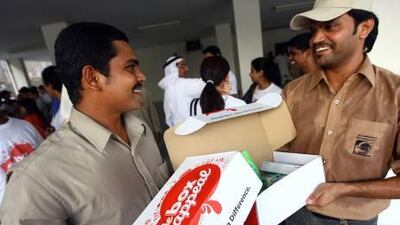 Dubai Municipality workers Mohideen. left, and Naseser were among more than 200 at their labour camp who received boxes containing everyday essentials such as toothpaste and t-shirts.