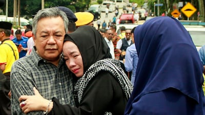 Nik Azlan Nik Abdul Kadir, father of one of the victims comforts his wife outside the Darul Quran Ittifaqiyah religious school in Kuala Lumpur. Sadiq Asyraf / AFP Photo