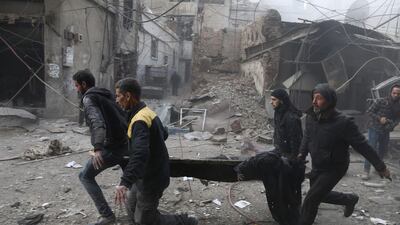 Syrian civil defence volunteers carry away an injured man after regime air strikes in Jisreen on February 8, 2018. Abdulmonam Eassa / AFP