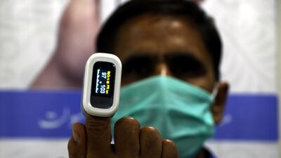 An Alkhidmat Foundation aid worker displays a pulse oximeter that the organisation gives out with oxygen cylinders. Imran Mukhtar/ The National