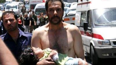 A Syrian man carries a wounded girl after an explosion that targeted a military bus in Damascus on Friday.