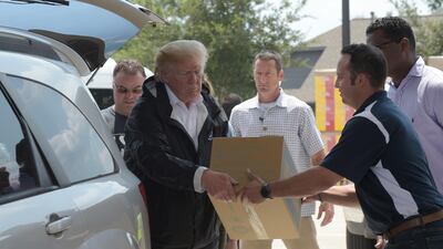 President Donald Trump helps load donated items for people impacted by Hurricane Harvey during a visit to First Church of Pearland in Pearland, Texas, Saturday, Sept. 2, 2017. (AP Photo/Susan Walsh)