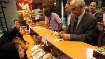 People stand in line at a currency exchange shop to purchase US dollars at a shopping centre in Tehran on October 5, as the US dollar fell after local banks sold the greenback to boost the Iranian rial.