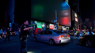 A police officer directs traffic with Times Square's dark billboards in the background after a power outage hit Manhattan in New York City. AFP