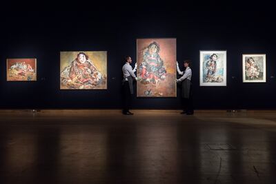 Art handlers hold a painting titled 'Grosse Puppe I (Large Puppet I)', 1979, by Marwan Kassab-Bachi. Getty Images