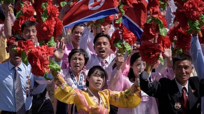 Participants wave flowers as they march past a balcony from where North Korea's leader Kim Jong Un was watching, during a mass rally on Kim Il Sung square in Pyongyang. AFP