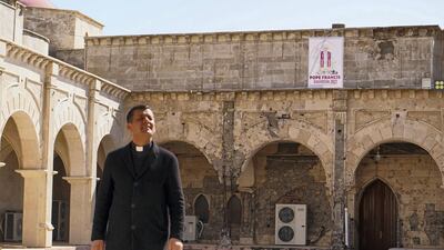 Father Ammar Yako, head of the Church of the Immaculate Conception, walks past a poster of Pope Francis days before his historic visit to Iraq. Getty