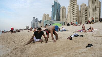 Riyaz Mahoo of India gets buried in the sand by friends along the shoreline at JBR. Mike Young / The National