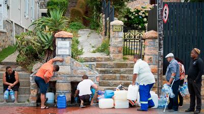 South Africans collecting drinking water from pipes fed by an underground spring, in St James, about 25km from the city centre in Cape Town / AFP