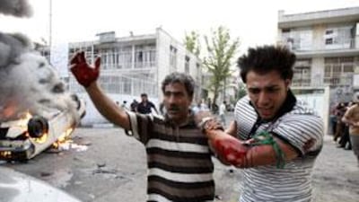 A protester allegedly injured by gunfire from pro-government militia is helped by another protester near a rally supporting leading opposition presidential candidate Mir Hossein Mousavi in Tehran, Iran, on June 15, 2009.