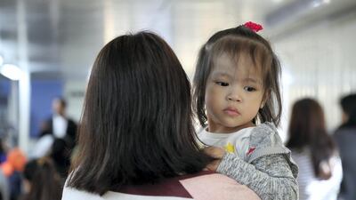 An expatriate mother holds her daughter while visiting the Philippine consulate in Dubai. Pawan Singh / The National