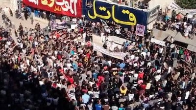 An image grab taken from a video uploaded on YouTube shows anti-regime protesters standing under banners that read in Arabic "Killer" and "Death rather than humilation" during a anti-government rally on the outskirts of Daraa Friday.