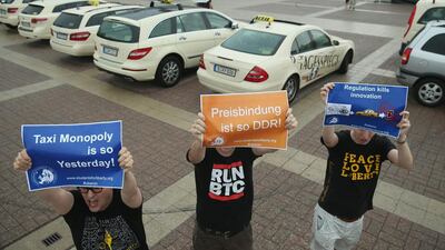 In Berlin, supporters of online ride-sharing apps hold up signs demanding an end to the taxi monopoly at a demonstration by taxi drivers at Olympia Stadium on June 11. Sean Gallup / Getty Images