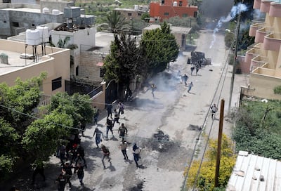 Palestinian protesters run for cover as Israeli forces fire tear gas during clashes in the West Bank . AFP