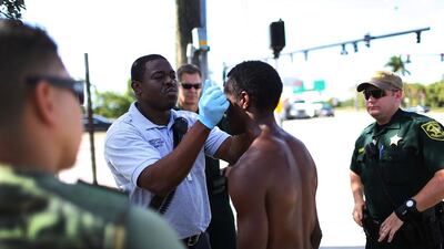 A paramedic takes the temperature of man suspected of being under the influence of flakka at Pompano Beach, Florida. Police officers surround the suspect in case he becomes violent. Joe Raedle / Getty Images