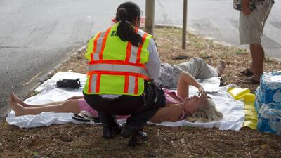 A paramedic checks on a woman, lying on a median, after she and others exited the Marco Polo apartment complex in Honolulu. Marco Garcia / AP Photo