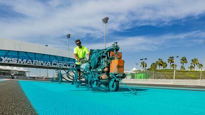 A worker fills in Yas's signature blue trackside decorations