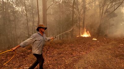 A man uses a water hose to battle a fire near Moruya, Australia. AP Photo
