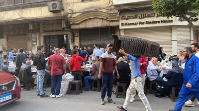 A volunteer brings out more plastic chairs to meet demand at an iftar on Bab El Louq street