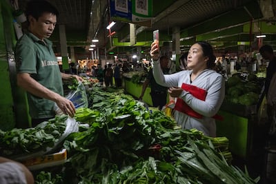 A customer scans a QR code to purchase vegetables at a wet market in Beijing. China's anaemic price changes contrast sharply with the surging inflation most other major economies have seen since the Covid-19 pandemic waned, forcing their central banks to rapidly raise interest rates. Bloomberg