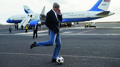 US Secretary of State John Kerry kicks around a soccer ball while talking on his mobile phone during an airplane refueling stop at Sal Island, Cape Verde, enroute to Washington, DC on May 5. Saul Loeb / AFP