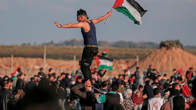 A Palestinian man carries the national flag during a demonstration near the fence along the border with Israel, east of Gaza City, on February 22, 2019. AFP/Mahmud Hams