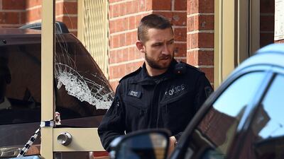 A policeman emerges from the block of flats being searched. William West.