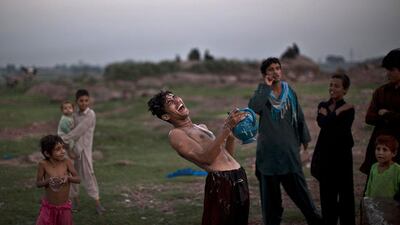 An Afghan refugee, who works at a wholesale fruit and vegetable market, laughs at a joke while showering at a public water point on the outskirts of Islamabad, Pakistan. Muhammed Muheisen / AP Photo