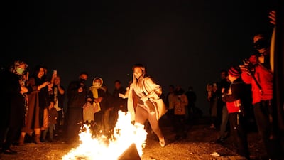 A girl prepares to jump over a fire, as onlookers watch, during Charshanbeh Suri celebrations in Tehran. EPA