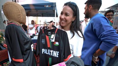 A woman holds up her new Palestinian top bought at the Reel Palestine souq