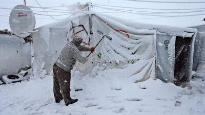 Near the town of Anjar, men used brooms and sticks to try to clear the heavy snow from the tops of refugee tents, fearing the weight might cause the shelters to collapse. Hussein Malla / AP Photo