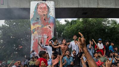 Protesters celebrate beside a defaced portrait of former prime minister Sheikh Hasina after news of her resignation, in Dhaka, Bangladesh. AP