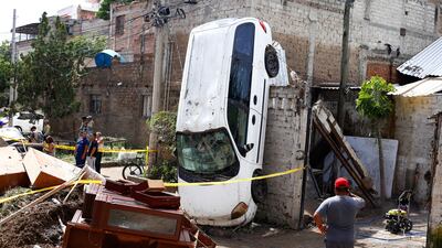 A man observes a car dragged onto a wall during flooding in the aftermath of heavy rains, in Zapopan, Mexico. Reuters