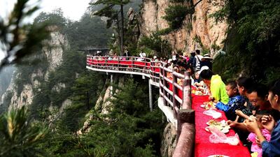 The diners dig into their meals among the pine trees on the cliff edge. AFP
