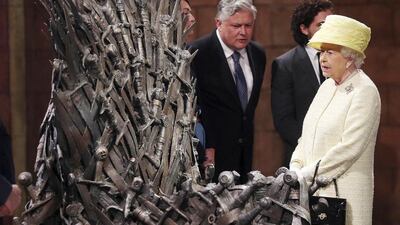 Britain’s Queen Elizabeth looks at the Iron Throne next to Game of Thrones cast members Kit Harington (2nd R), Conleth Hill and Lena Headey, on the set of the television series in the Titanic Quarter of Belfast, Northern Ireland, June 24, 2014. Reuters