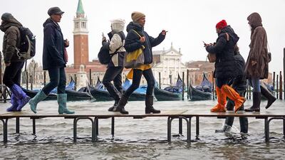People walk on benches through floodwaters. EPA