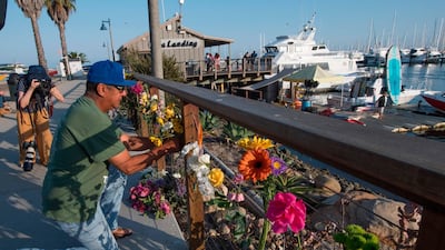 A man places flowers at a memorial wall near the Truth Aquatics moorings in Santa Barbara, California. AFP