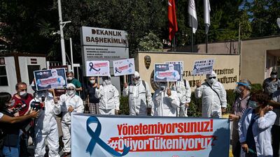 Turkey's health workers and doctors wearing personal protective equipment protest against government's policy in front of Istanbul University medical faculty. AFP