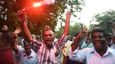 A supporter of ousted Sri Lanka's prime minister Ranil Wickremesinghe holds a flare and shout slogans with other supporters as they celebrate Sri Lanka's Supreme Court ruling outside the Sri Lankan Supreme Court in Colombo on December 13, 2018. Sri Lanka's Supreme Court on December 13 ruled that President Maithripala Sirisena's sacking of parliament last month was illegal, clearing the way for potential impeachment proceedings against him. / AFP / ISHARA S. KODIKARA