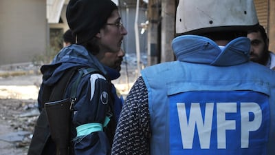 A United Nations World Food Programme worker talks to rebel fighters on February 8, 2014 on the second day of a humanitarian mission in a besieged district of the central city of Homs, Syria. AFP