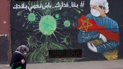 A woman walks past writing on a wall that encourages people to stay at home to prevent the spread of coronavirus, in Sale, Morocco. EPA