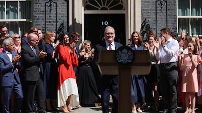 Mr Starmer is applauded as he walks out of No 10. EPA